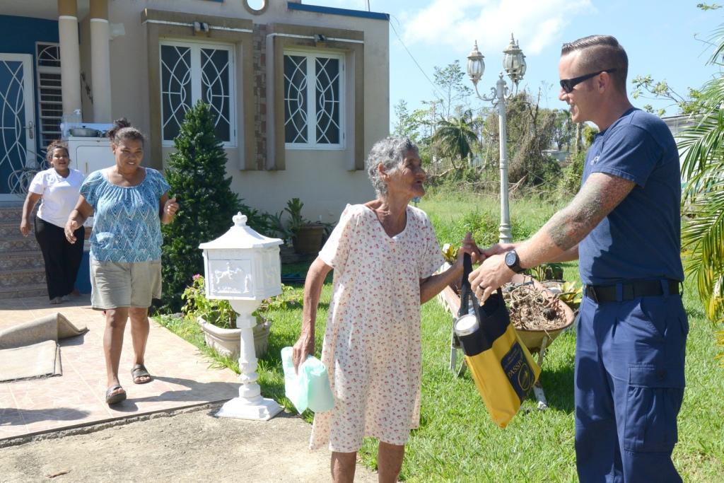 Coast Guard Chief Petty Officer Dave Warner, chief of the Aviation Survival Technician Shop at Coast Guard Air Station Borinquen in Aguadilla, Puerto Rico, delivers aid to a family in Aguadilla, Oct.