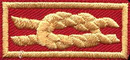 It is to be worn in place of, not in addition to, the normal Eagle knot. The very first edition of this knot was oversize, badly so, and was recalled. See Part 3.