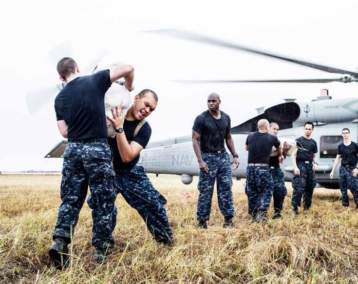 Sailors assigned to an aircraft carrier load relief supplies onto an MH-60R Sea Hawk helicopter to be airlifted to local villages during Operation Damayan. (U.S. Navy photo by Mass Communication