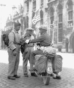 MEMBER OF CANADIAN PROVOST CORPS TALKING TO MEMBERS OF THE BELGIAN RESISTANCE, BRUGES, SEPTEMBER 1944.