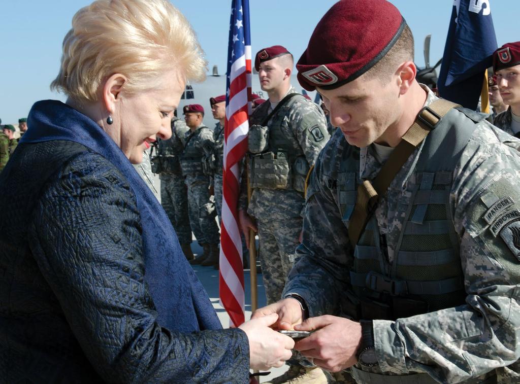 ASSURANCE IN EUROPE A paratrooper from the 173rd Airborne Brigade Combat Team presents a patch to Lithuanian President Dalia Grybauskaitė during a welcome ceremony 26 April 2014 at Siauliai Air Base,
