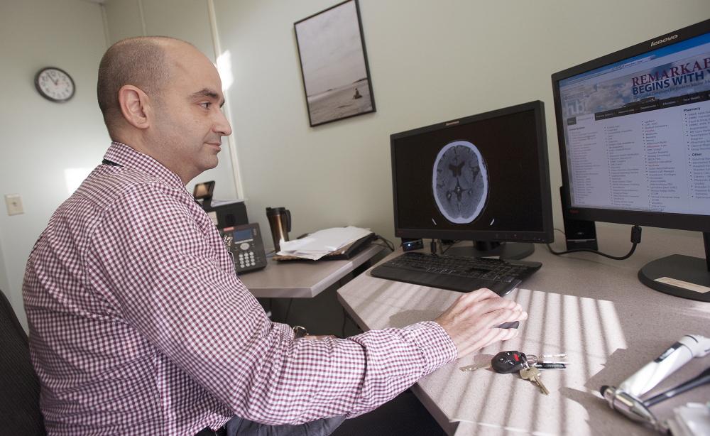 Dr. Tarek Wazzan, medical director of Eastern Maine Medical Center s stroke care center, reviews information in his