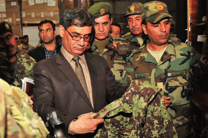 SECURITY Afghan Minister of Defense Tariq Shah Bahrami examines an ANA uniform during a visit to the Central Supply Depot in Kabul. (RS photo by Sgt. First Class E.L.