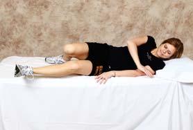 At the same time you are lowering your upper body, bring your hips, knees and feet together up onto the bed.