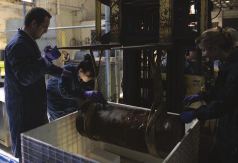 An NHHC archaeological team prepares to store a section of a late 19th century Howell torpedo in a desalination bin.