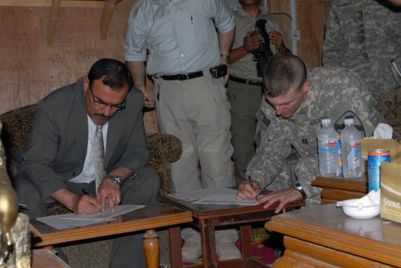 s out of the cities Right: Sameer al Haddad, representative from the Office of the Prime Minister, signs the ownership paperwork transferring the responsibility of Joint Security Station Sadr City