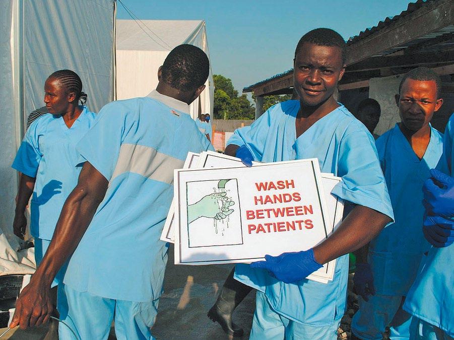 AN EBOLA RESPONDER SHOWS OFF A HAND-WASHING SIGN AT THE OPENING OF THE SINJE ETU IN LIBERIA.