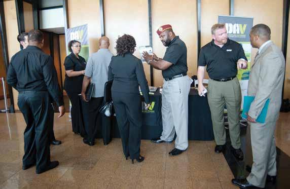 DAV representatives, including Senior Vice Commander Moses McIntosh (center), inform attendees about the organization s services at the inaugural DAV/RecruitMilitary All Veterans Career Fair, which
