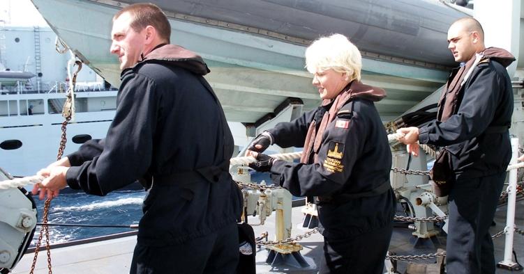 Cheryl Gallant, centre, MP for Renfrew-Nipissing-Pembroke, helps haul on a line aboard HMCS Vancouver. those onboard.