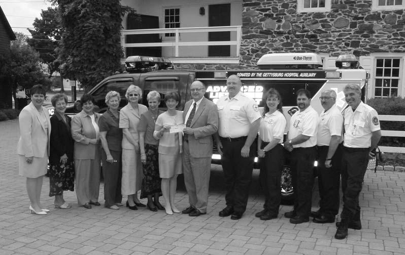 Member of the hospital Auxiliary present a check to Hospital President Steve Renner at dedication ceremonies of the present day 2003 medic unit.