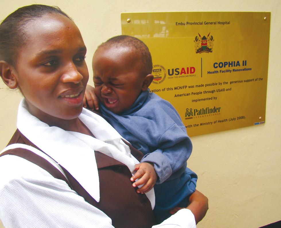 A woma ad her child stad ext to the recetly reovated MCH/FP cliic at the Embu Provicial Geeral Hospital i Easter Provice. The reovatios were fuded by USAID through the COPHIA II project.