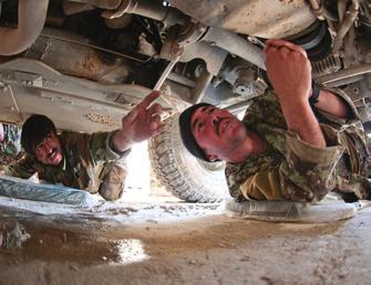 A driver with the Afghan National Army s 6th Kandak assists another driver in repairing a Humvee.