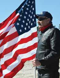 of the 100 mile relay. Keep it Photo by WALLACE McBRIDE A member of the American Legion Riders holds a flag for the runners arriving at the end of the 100-mile relay March 15 at Hilton Field.