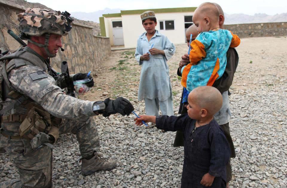 A U.S. Army Cavalryman hands out some ink pens to children in Charkh Valley, Logar Province, Afghanistan, 18 June, 2010.