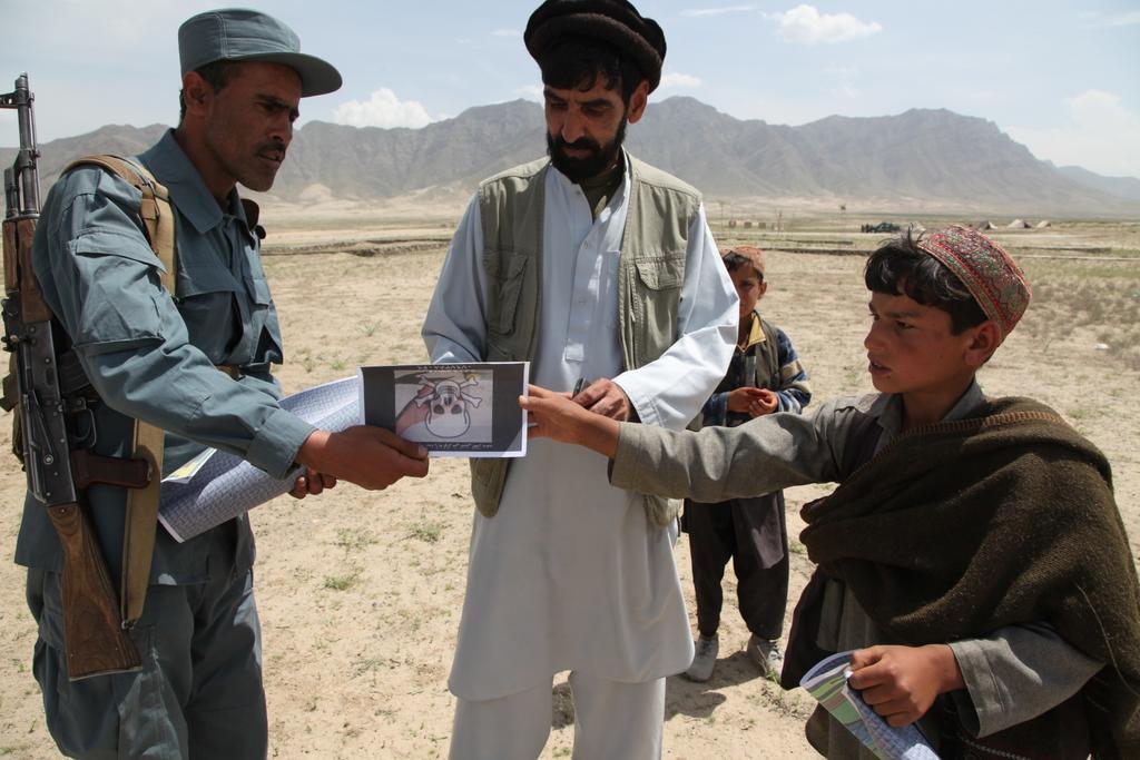 Apache Troop 1-75 Conducts Route Clearance An Afghan Uniformed Police officer distributes posters to locals of a village near Bagram Air Field, Parwan province, Afghanistan, May 1, 2014.