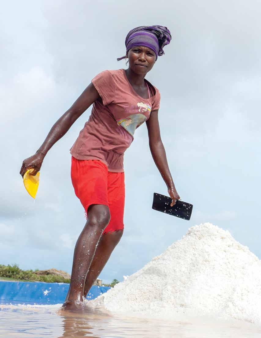Mawutor gathering salt from the bottom of a concentrator pan at a salt production operation near