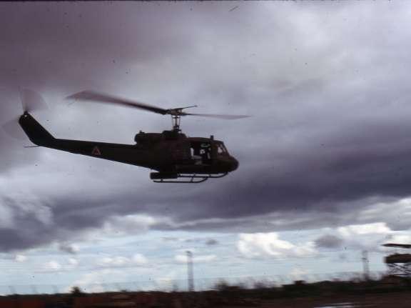 Soc Trang Army Airfield Rain clouds appear ominous as a Huey equipped with rocket pods flies past a sentry tower.