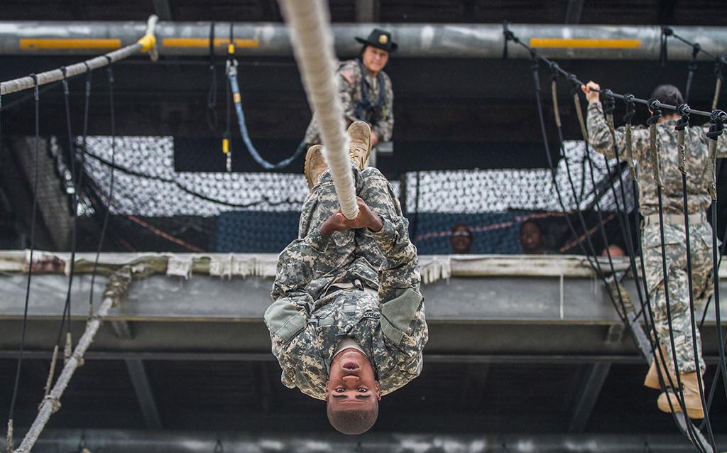 After losing his balance on a rope bridge obstacle, a Soldier in Basic Combat Training with E Company, 2nd Battalion, 39th Infantry Regiment, attempts to complete the task by using pure upper body