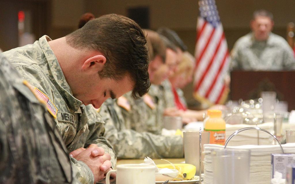 A soldier from the 79th Ordnance Battalion bows his head as 1st Lt. Michael Will, chaplain, gives the invocation before the prayer breakfast at the Operation Iraqi Freedom Dining Facility on Feb.