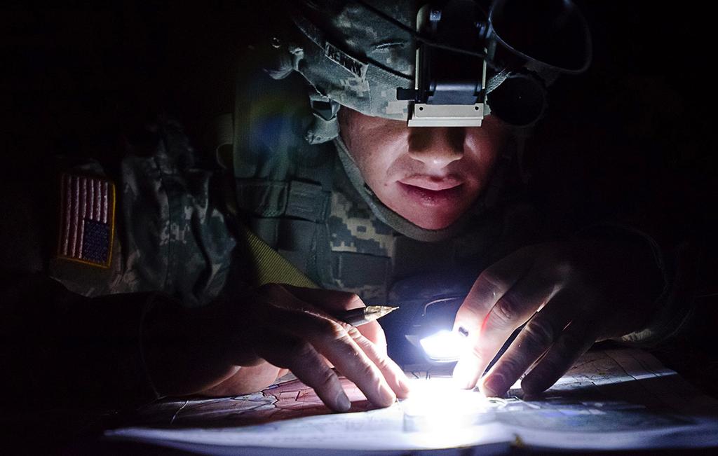 Spc. Randall Reinink, a parachute rigger representing the 143rd Sustainment Command (Expeditionary), plots points by flashlight during a night land navigation event during the 377th Theater