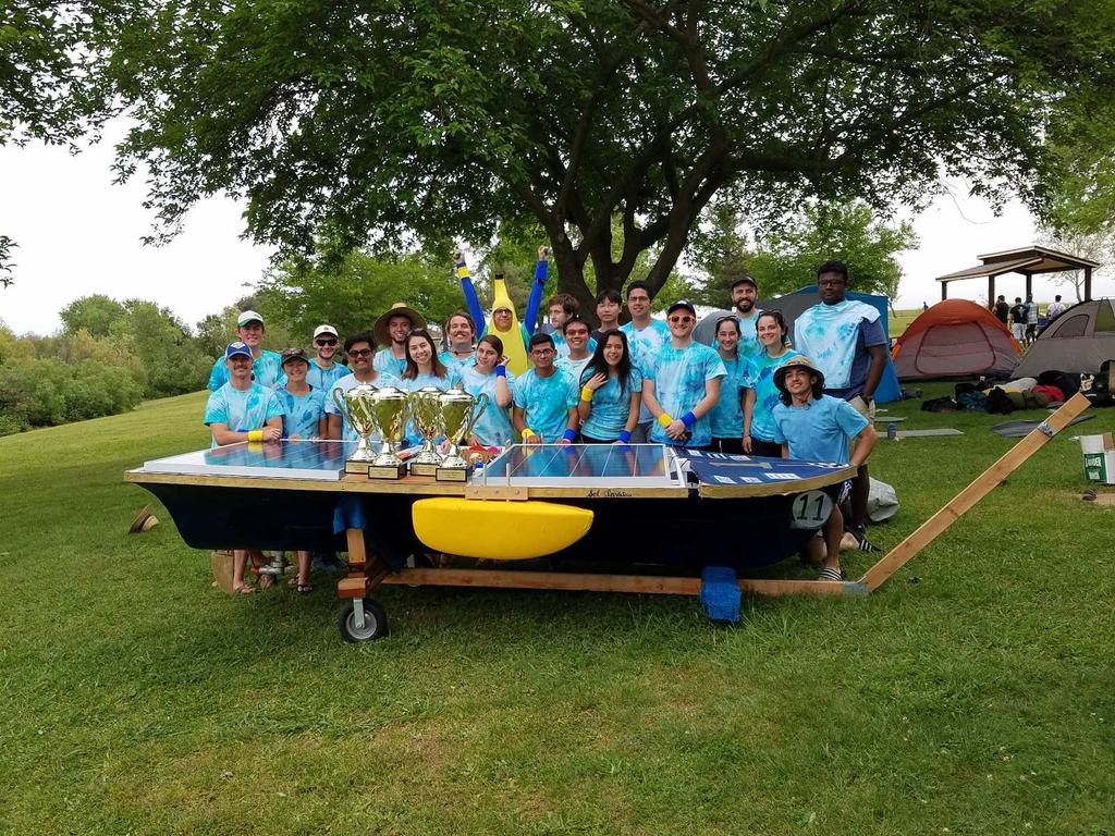 The Davis Solar Boat team poses behind their 2018 boat, Sol Invictus, with their four trophies for Best Technical Design, Best Boat Design, Best Artistic Design, and the Spirit Award.