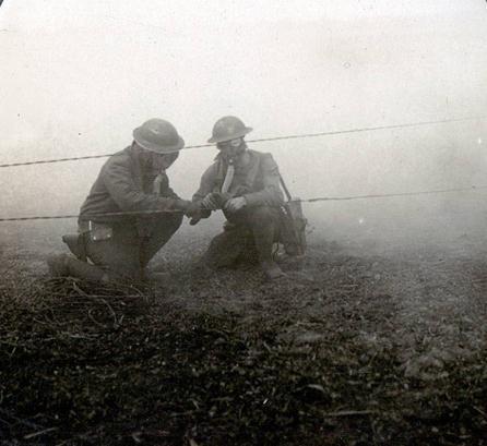 Repairing field telephones lines during a gas attack at the front The American soldiers working before us, safe from the gas hanging thickly