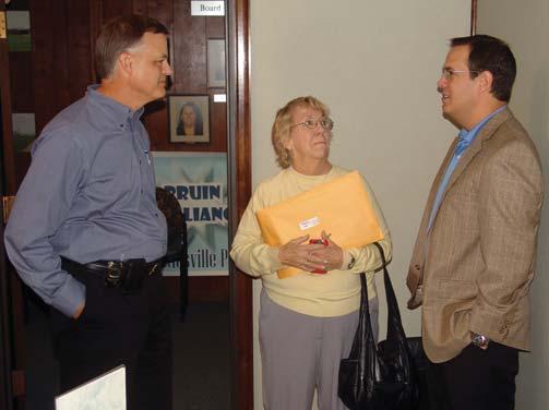 Tyler Vaclaw (pictured right) talks to Bartlesville Board of Education vice president Doug Divelbiss and president Marta Manning on Thursday during his retirement ceremony, which was held in the