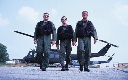 At right, Air Force helicopter pilots (l-r) Capt. Carey Johnson, 1st Lt. James Mc- Cue, and Capt. Randy Voas return after a training sortie.