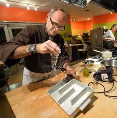 Include: Photo: Chef Olive adds a finishing touch to a dish at the Kitchen on Fire Cooking School (North Berkeley).