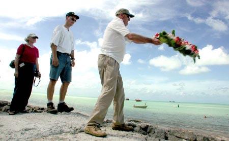 Leroy Kisling, right, tosses a wreath off of Red Beach No. 2 on Betio Island and into the Tarawa Atoll lagoon Nov.