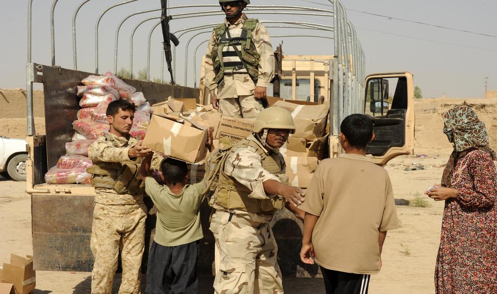An Iraqi family receives food from Iraqi Army soldiers and Peshmerga troop member in a small village in Diyala Province, Iraq, September 4, 2010.