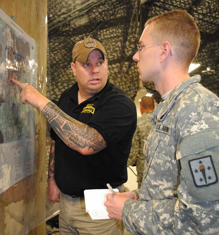 Bucky Roughton, a tactics instructor, goes over a mission route with 2nd Lt. Thomas Ivey during the tactical operations center cycle of the Basic Officer Leader Department field training exercise.