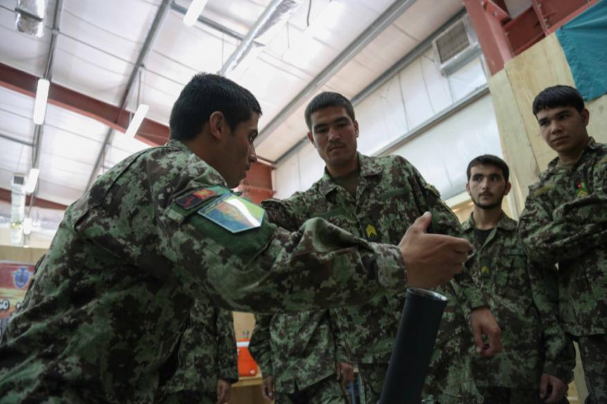 An Afghan National Army (ANA) soldier with the 201st Corps, demonstrates the process of loading a 60mm mortar tube during a simulated mortar training exercise at Forward