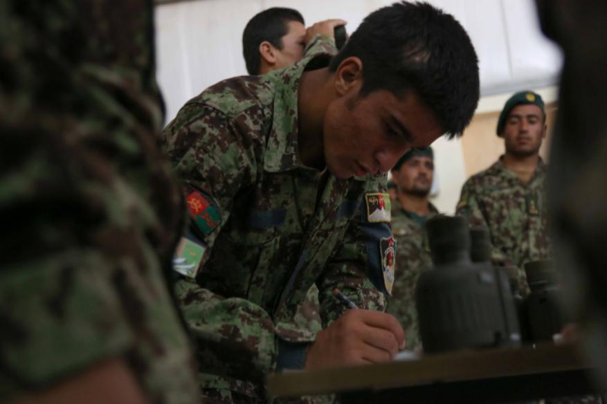 An Afghan National Army (ANA) soldier, 201st Corps, adjusts his coordinates for a call for fire exercise during a field artillery instructor graduation ceremony at Forward Operating Base