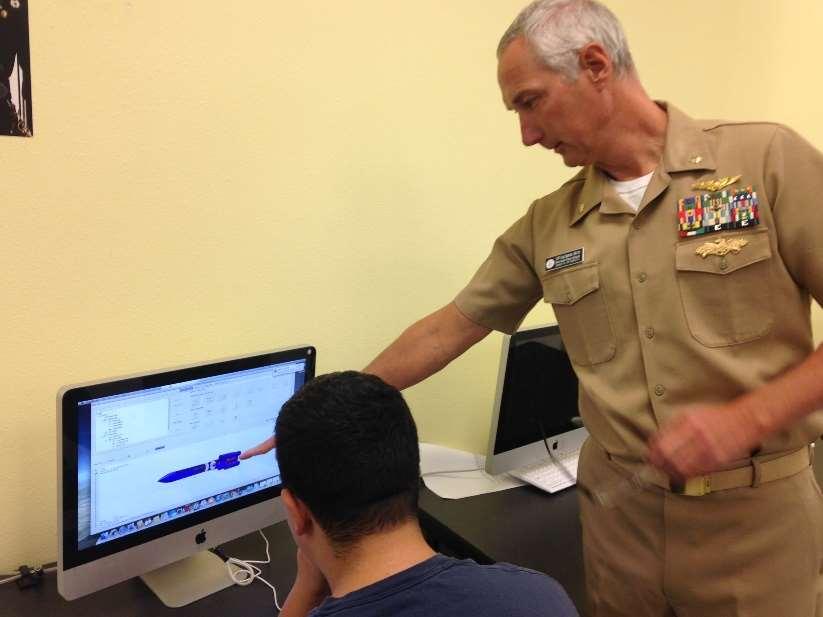 Craig Stapleton Senior Naval Science Instructor at work explaining model rocket design to an NJROTC student (2017). (Photo: Sr. Master Sgt.