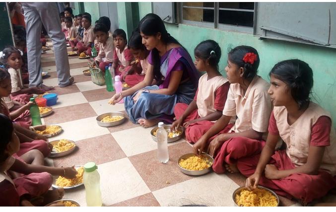 Tmt.B. Rohini, I.A.S., District Collector Salem who inspected the Noon Meal centre at Peddanaicken palayam in Salem District relishing the Mid Day Meal along with the Noon Meal beneficiaries.