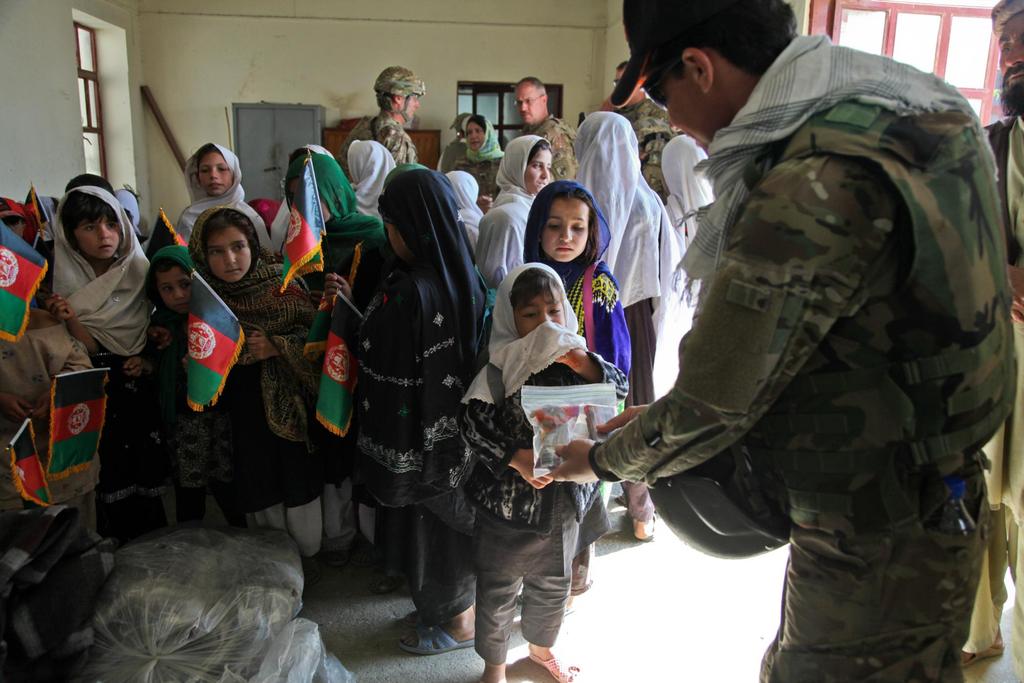 An interpreter serving with Provincial Reconstruction Team (PRT) Khost offers some candy to the children at Khost city orphanage, Khost