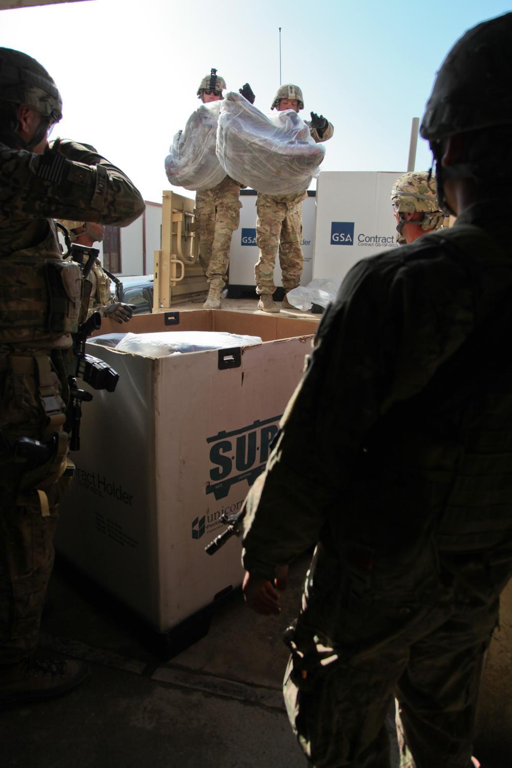 U.S. Soldiers serving with Provincial Reconstruction Team (PRT) Khost unload blankets off of a light medium tactical vehicle during a humanitarian aid mission at the Khost