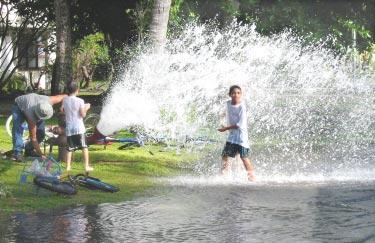 Third-grader Jeffery Pippitt turns one man s job into an opportunity to play as he splashes with delight in the spray produced by a fire hydrant that s being flushed out by Dave Dennis, at left,