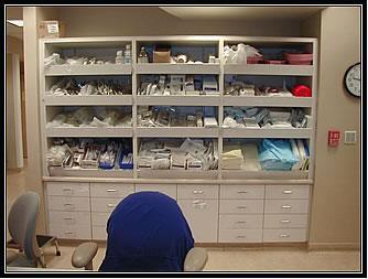 Supplies including linens and various medical products are retrieved from their respective cabinets.