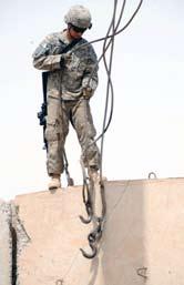 , sits atop a concrete barrier after unhooking cables used to lift the barrier to a new position. Spc.