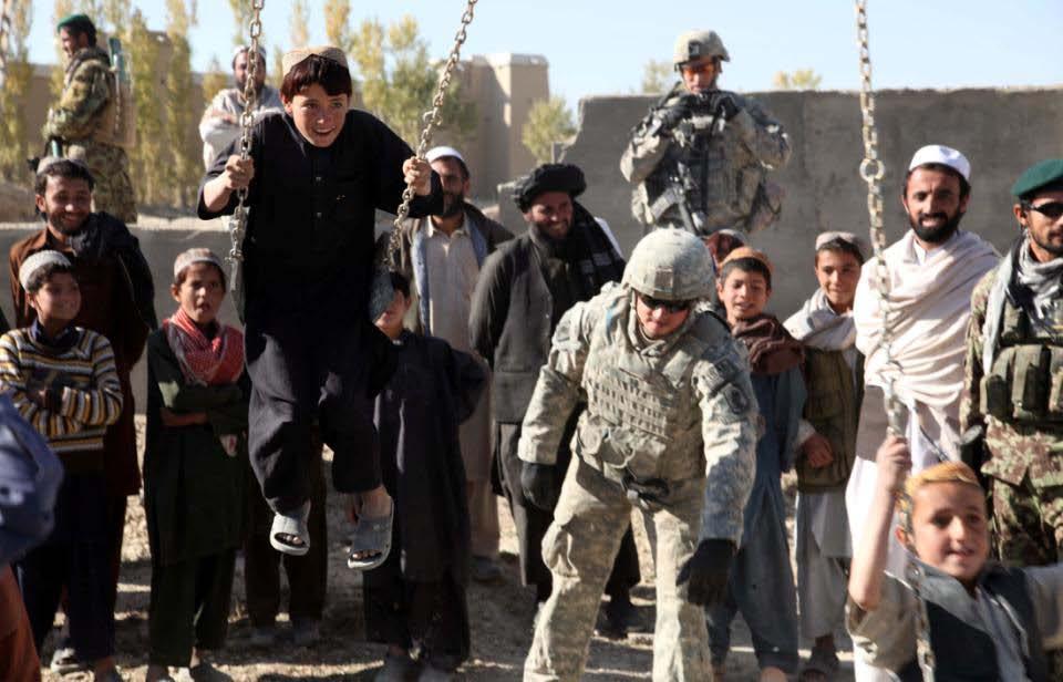 U.S. Army Spc. Zachary McNeil of the 173rd Airborne Brigade Combat Team, 1st Squadron, 91st Cavalry Regiment, Comanche Troop pushes Afghan children on swings.