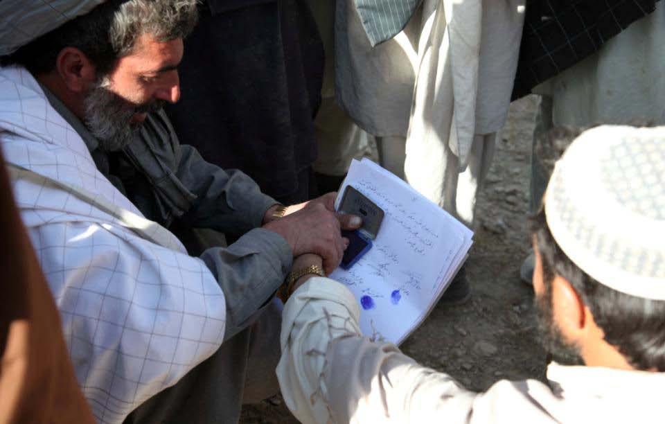 Villagers from Mangokhel give their thumb print to Farooq Hamyoon, the Kherwar District Governor.