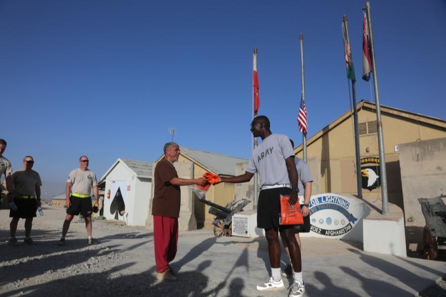U. S. Army 1st Sgt. Amara Fofona gives a t-shirt to an Afghan National for participating in the run at Forward Operating Base Lightning, Paktya province, Sept 11, 2013.