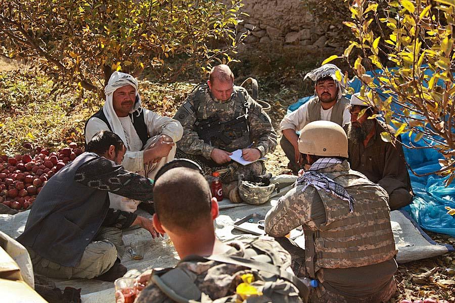Local farmers sit with Coalition Forces as they discuss ways of improving the village's water