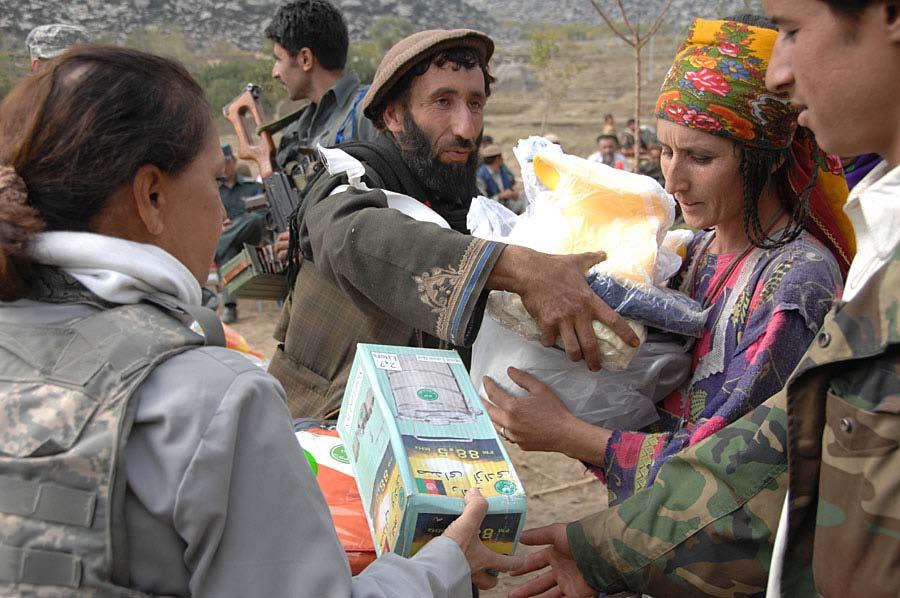An Afghan woman form the Dudarek village is handed a pile of items given during a humanitarian aid handout angled towards women in the Wagel valley,
