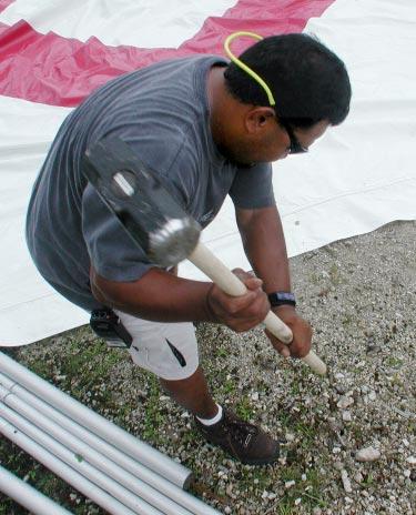 down a tent spike last Tuesday in preparation for the Fourth of July celebration at Emon Beach.
