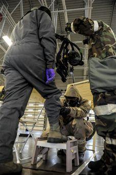 Senior Airman Roger Adams (middle), an Aircrew Flight Equipment specialist assigned to the 4th Operations Support Squadron, performs decontamination measures on Airman 1st Class Kyle Rogers (left),