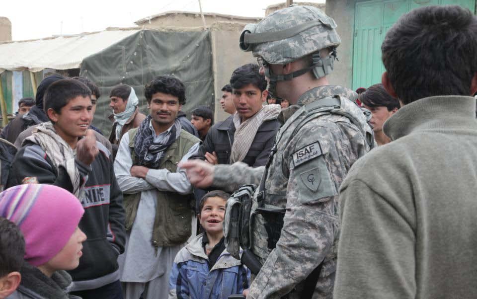 Spc. Brandon Keesler attempts to show an Afghan local national child a hand game at a local bazaar in a village near Bagram Airfield, Parwan province, Afghanistan, Feb.
