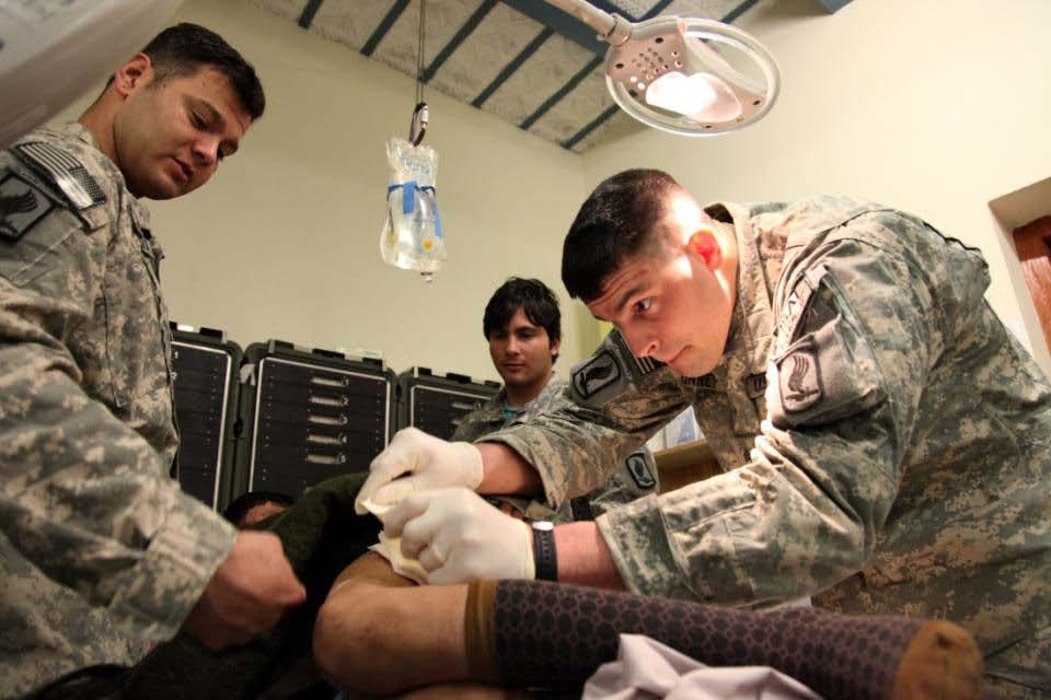 Medics from Headquarters and Headquarters Company, 2nd Battalion, 503rd Infantry (Airborne) bandage a local Afghan boy after he was hurt carrying